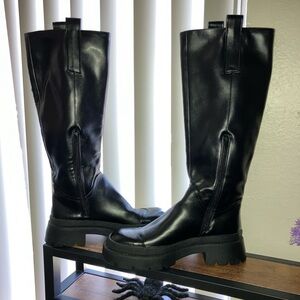 Black knee high rain boots. Straps on top to pull up over feet. Zipper on side.